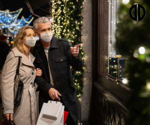 A couple wearing masks admiring a store's holiday display