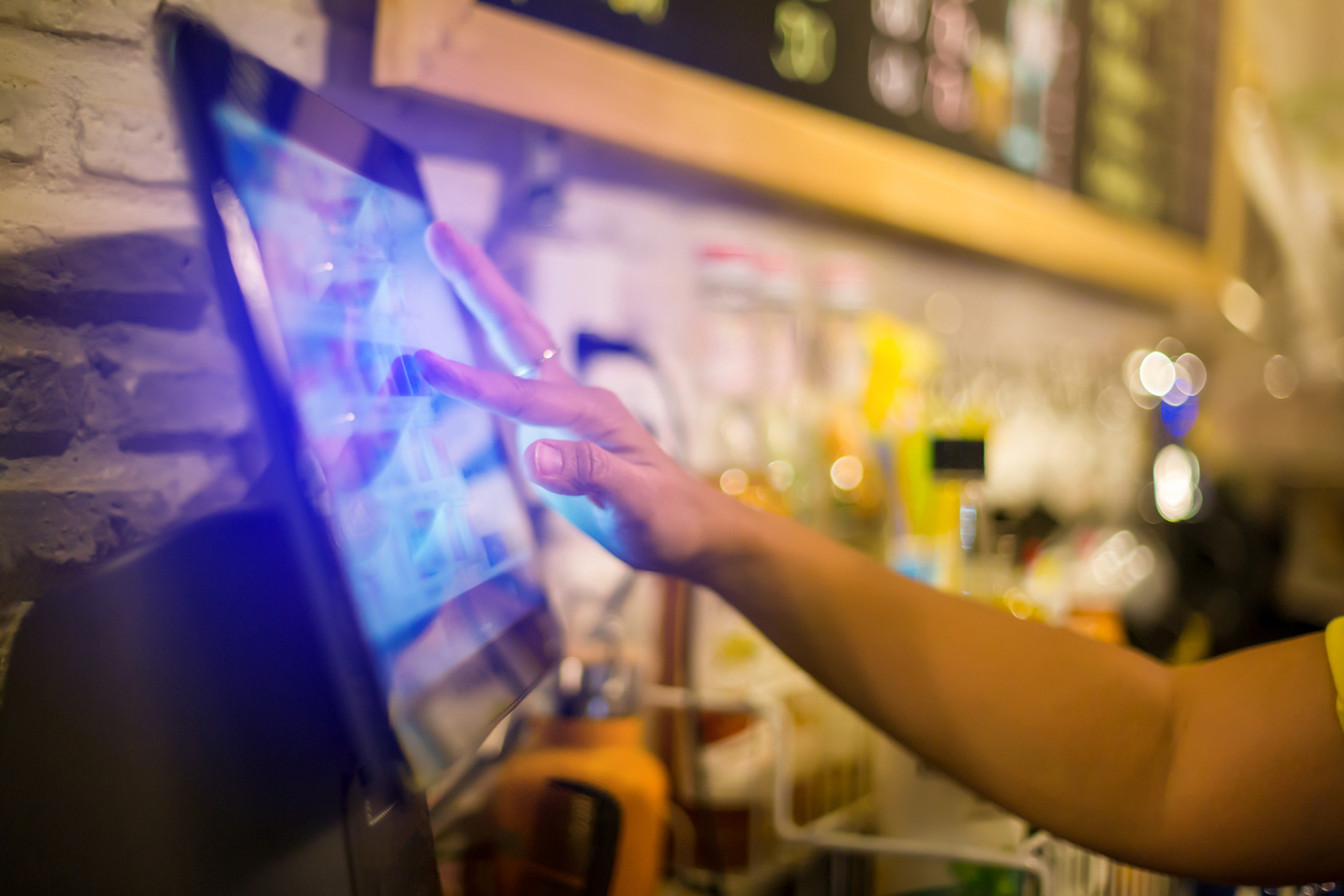 Blurry picture of cashier is making order on touch screen of computer in cafe or store.