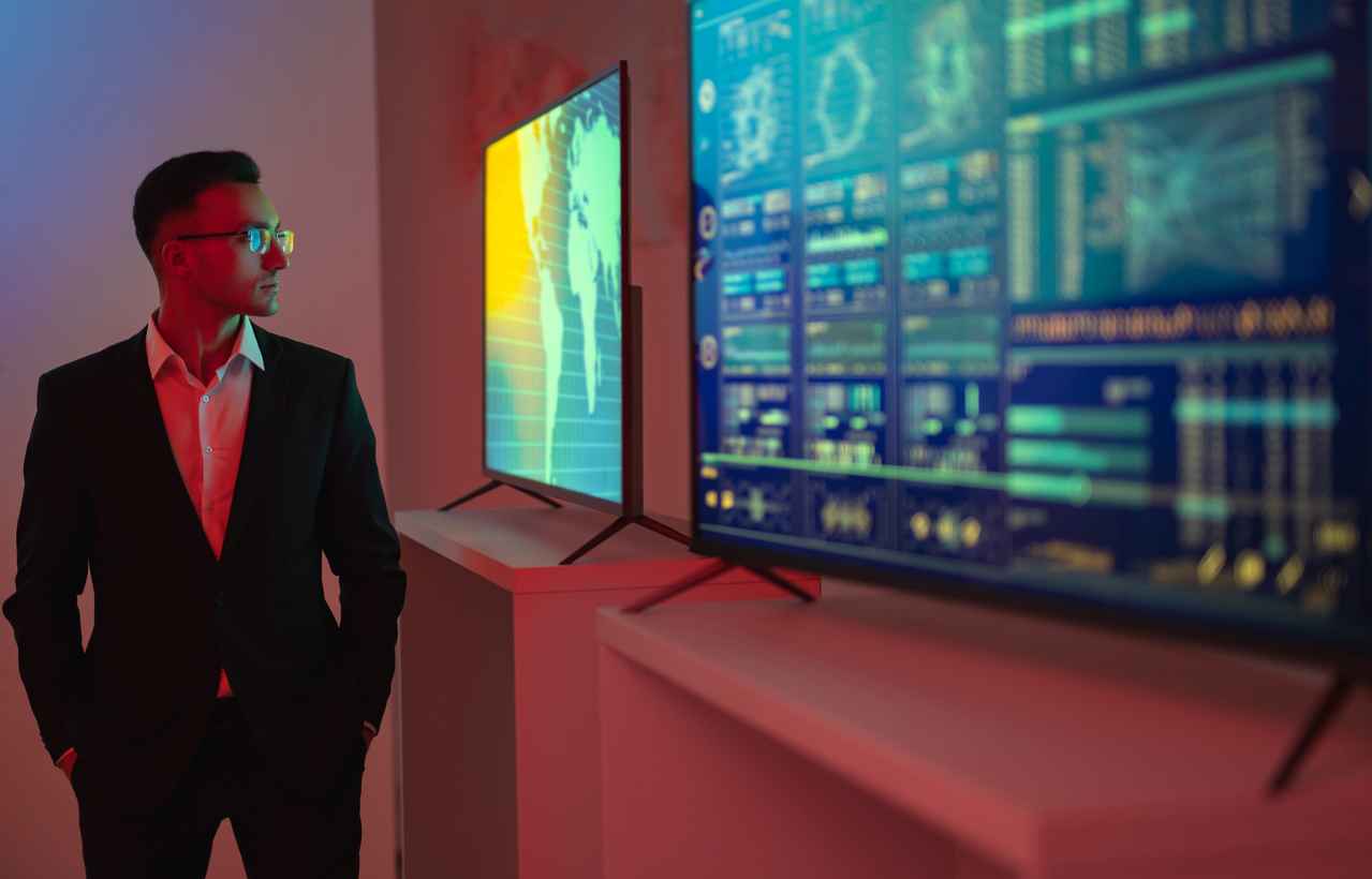 The businessman standing near screens with graphs, maximizing digital display lifespan