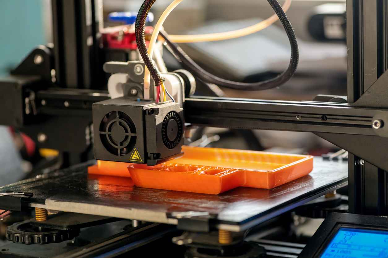 The 3D printer prints orange plastic model. modern technology; rapid prototyping