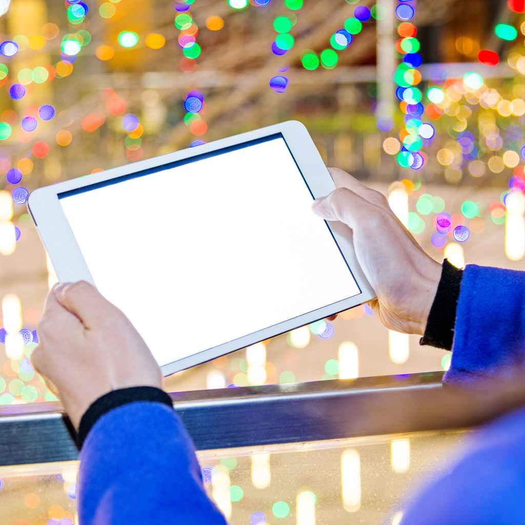 woman using a digital tablet at night with colorful lights in the background