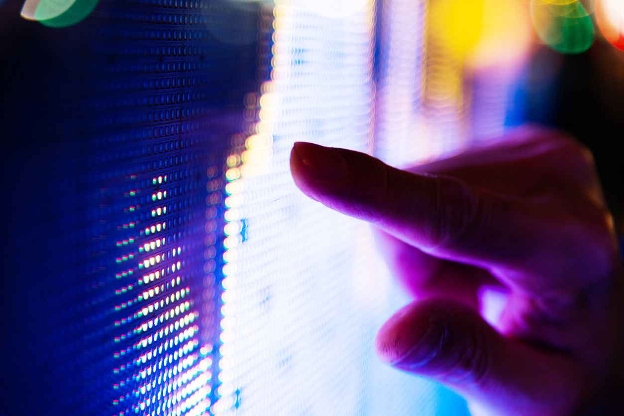 Man finger pointing at LED screen of stock market price at night.